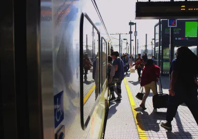 People boarding Los Angeles Metro train on outdoor platform.