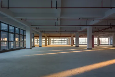 Large empty office building floor with columns and golden hour light.