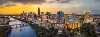 Austin, Texas skyline with river in foreground at sunset.