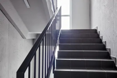 View of plain building staircase with light coming in from window on landing
