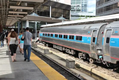 Passengers walking on platform at Boston train station with Amtrak train parked on track.