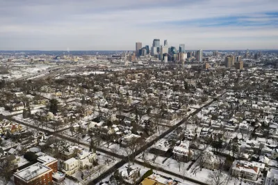 Aerial view of Minneapolis neighborhood and downtown skyline in winter with snow.