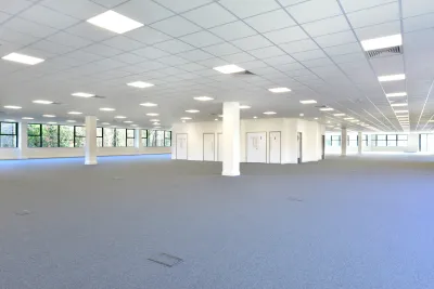 Empty open plan office with gray carpet and white walls
