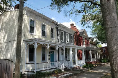 Historic homes with intricate white trim on tree-lined street in Richmond, Virginia.