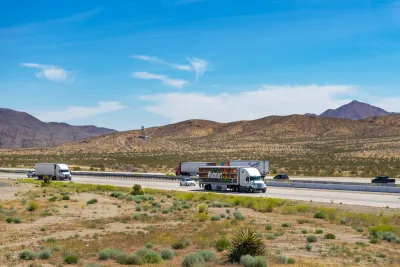 View of trucks on Interstate 15 with desert mountains in background in Southern California.