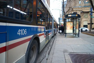White, blue, and red Chicago transit bus at an urban bus station with shelter.
