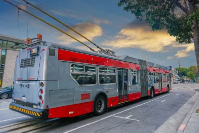 Red and silver Muni trolley bus connected to overhead wires on San Francisco street