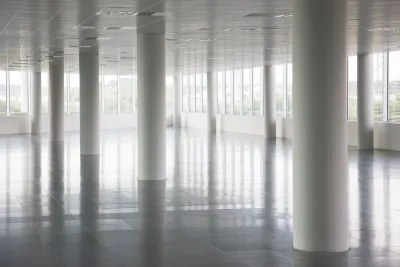 White round pillars in empty office building with windows across all walls and white floors and ceiling.