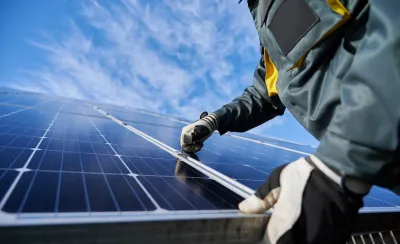 Close-up of technician wearing gloves installing photovoltaic solar panel.