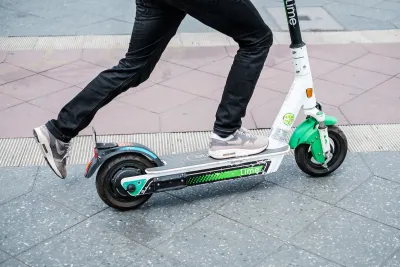 Close-up of person riding green and white Lime e-scooter.