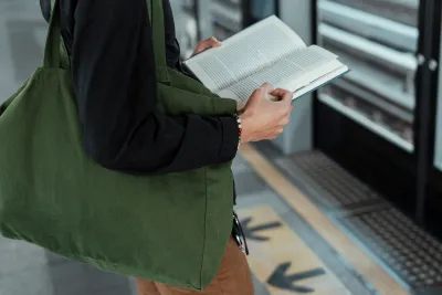 Close-up of person standing and holding book on train platform.
