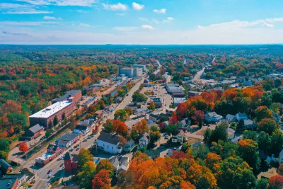 Aerial view of small New Hampshire town with brick buildings and fall foliage.