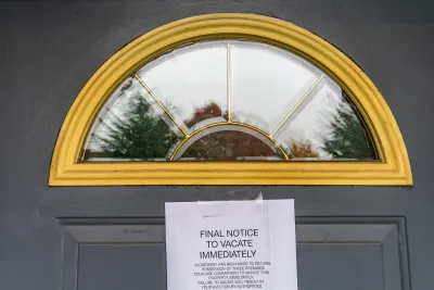 Eviction notice taped to dark grey door with arched window at top.