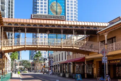 Commercial street in Orlando, Florida with elevated pedestrian walkway crossing the street at Church Street Station historic train station and commercial hub.