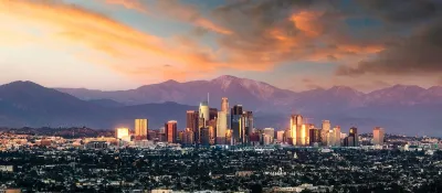Los Angeles, California skyline against mountains at sunset.