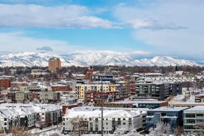 View of snowy buildings and mountains in background in Denver, Colorado.