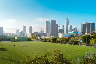Green grass soccer field with Los Angeles skyline in background.