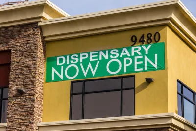 Green "Dispensary Now Open" banner on tan/orange building.