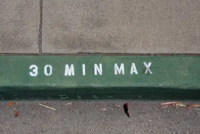 Close-up on green painted curb with '30 min max' in white.