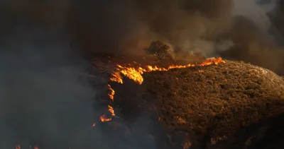 Line of wildfire moving across dry hillside in Malibu, California during 2018 Woolsey fire.