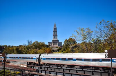 Amtrak train passing on bridge with historic tower in background in Alexandria, Virginia.