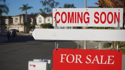Close-up on red and white "Coming Soon" and "For Sale" signs in front of single-family homes on sunny day.