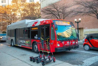 Red public bus on street in San Antonio, Texas with line of four red e-scooters on sidewalk.