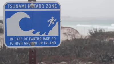Close-up of blue and white tsunami warning sign on coast in Monterey, California on gloomy day.