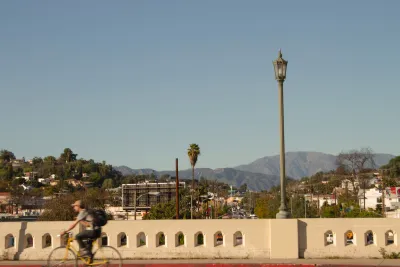 One cyclist on yellow bike crossing vintage concrete bridge in East Hollywood, Los Angeles, California.