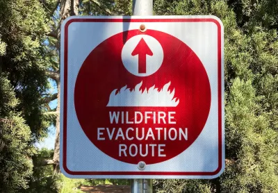 Red and white "Wildfire Evacuation Route" sign on signpost.