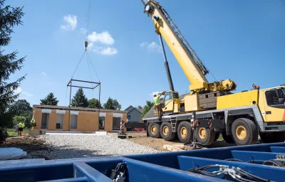 Modular home under construction with crane dropping in components.