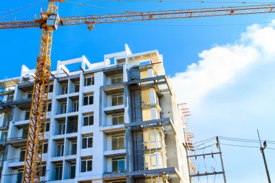Multistory apartment building under construction with yellow crane.