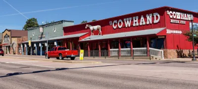 Single-story western-style buildings in Woodland Park, Colorado. Red building on corner labeled "COWHAND" in white text.