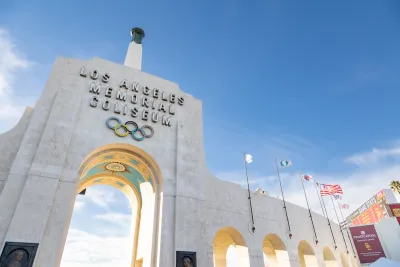 View looking up at stone entrance arch with name and Olympic rings at Los Angeles Memorial Coliseum.