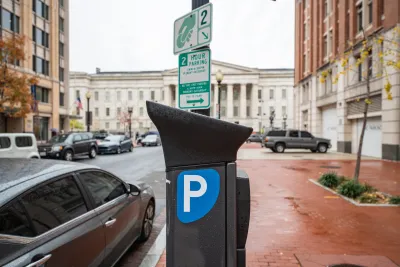 Electronic parking pay station next to curb in Washington D.C., on rain-soaked red brick sidewalk with neoclassical white building in background