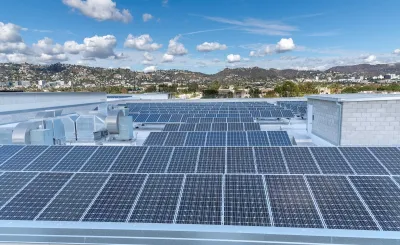 Large roof with solar panels and Los Angeles hills in background.