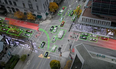 Aerial view of vehicles on city street with superimposed graphic arrows indicating autonomous cars.