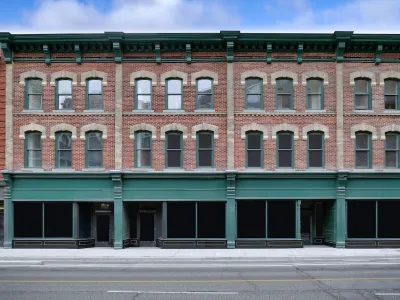 Brick building with storefronts on ground floor and apartments on two floors above.