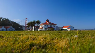 Green lawn with historic buildings and Golden Gate Bridge in background in Presidio national park site in San Francisco, California.