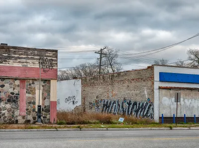 A vacant lot between two one-story brick buildings with graffiti in Detroit, Michigan
