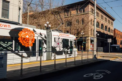 White Seattle streetcar at mid-street stop with four-story brick building in background