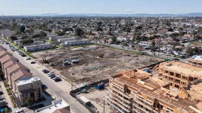 Aerial view of large construction site and vacant, graded lot next to public housing buildings in Watts, Los Angeles, California.
