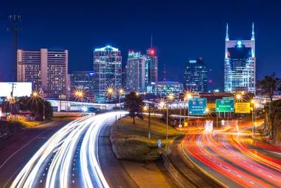 View of Nashville skyline at night with blurred highway lights in foreground.