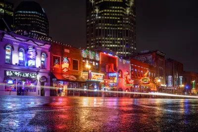 View from street level of brightly neon-lit bars and theaters on Broadway in downtown Nashville, Tennessee.