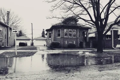 Sepia-toned photo of flooded street with residential home
