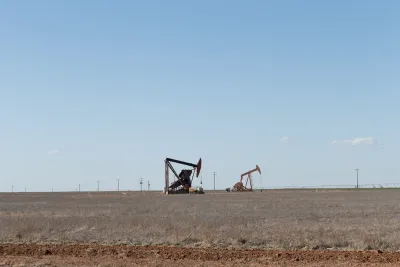 Two oil drilling derricks in vast field in West Texas.