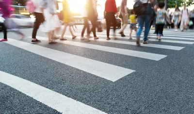 Close-up of blurred pedestrians crossing busy urban crosswalk.