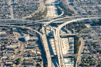 Aerial view of massive Los Angeles freeway interchange with dense housing and industrial areas around it.