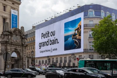 Large Airbnb billboard on neoclassical apartment building in Paris, France.