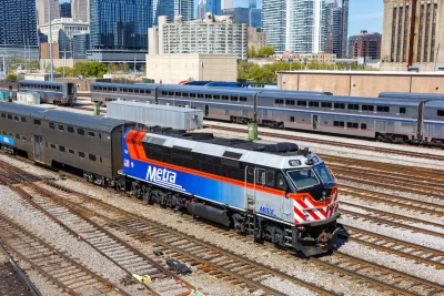 Blue, white, and red Metra commuter train with Chicago buildigns in background.